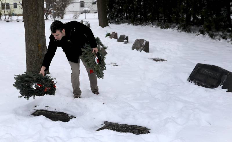 Austin May lays a wreath at a veteran’s gravesite during McHenry's Wreath Laying Ceremony in honor of fallen veterans on Friday, Dec. 5, 2025,, at St. Mary's Catholic Cemetery in McHenry. The event was hosted by McHenry American Legion Post 491 and Team Home Depot.
