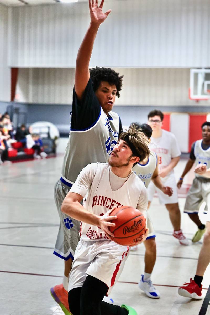 PCA's Jed Johns drives on Princeton's James Romano in Thursday's JV game at PCA's Howard Hoffman Memorial Gymnasium.