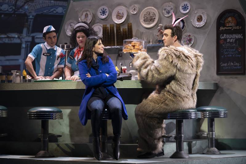Alex Syiek (right) plays TV weatherman Phil Connors and Phoebe González plays Phil’s producer, Rita, in Paramount Theatre’s Midwest regional premiere of Groundhog Day: The Musical, playing now through March 13, 2022. Also pictured, behind the counter: Matthew Bettencourt (left) as Jeff and Teressa Rose LaGamba as Doris. For tickets and information, visit ParamountAurora.com, or call the Paramount box office, (630) 896-6666. Credit: Liz Lauren