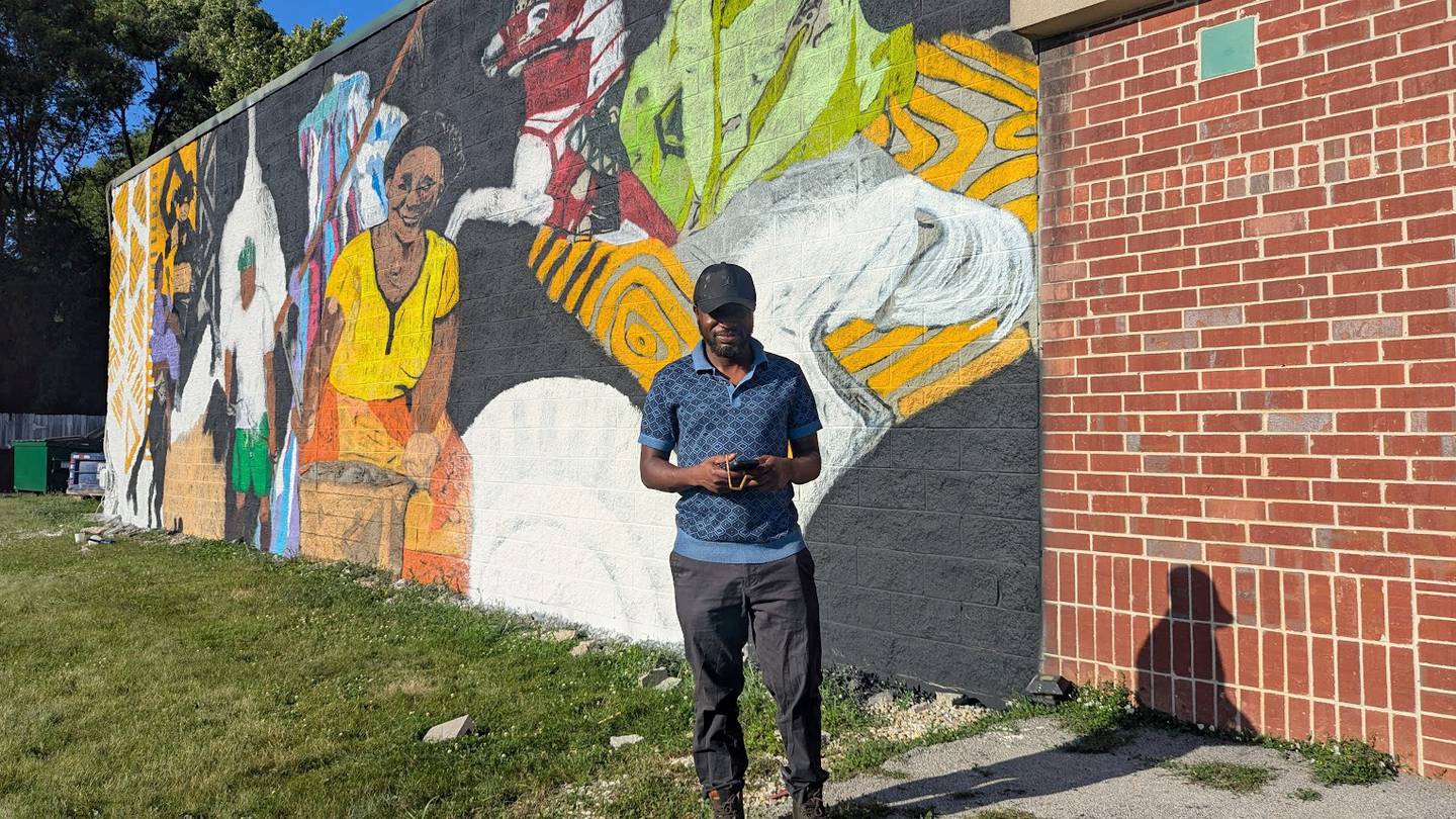 Uprizn Ikpemi, 40, of South Holland, a Nigerian-born American visual artist, muralist and art teacher, stands near his mural on Monday, June 23, 2025, at.3109 Theodore St. in Joliet. The owner of the future O’Larry Asun Spot, a halal restaurant that will feature West African dishes, hired Ikpemi to paint the mural on the side of the restaurant.
