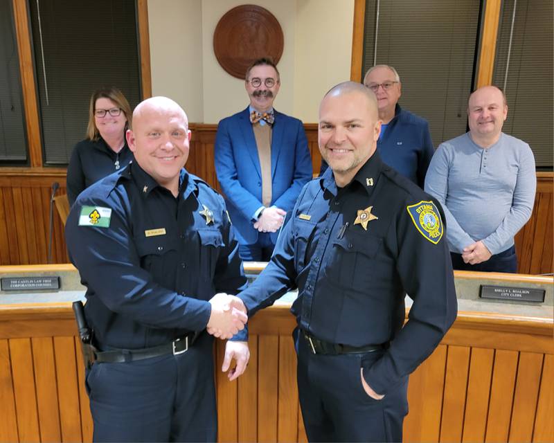 New Ottawa Police Chief Mike Cheatham (front, right) is congratulated by outgoing chief Brent Roalson at Tuesday's City Council meeting. Also pictured are (from left) Commissioner Marla Pearson, Mayor Robb Hasty, Commissioner Wayne Eichelkraut and Commissioner Tom Ganiere.