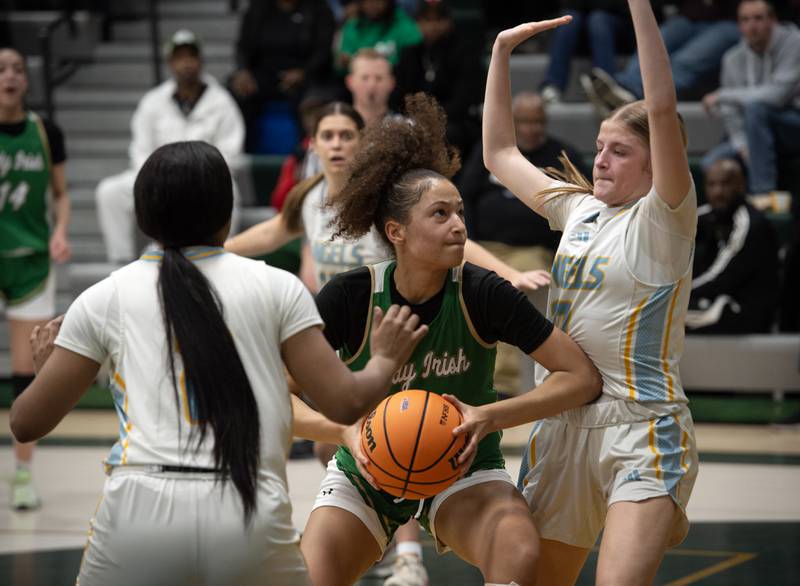 Bishop McNamara's Trinitee Thompson, center, works her way to the net as Joliet Catholic's Emma Napier, right, and Gabrielle Gavin guard during the Class 2A Regional Championship on Thursday, Feb. 19, 2026.