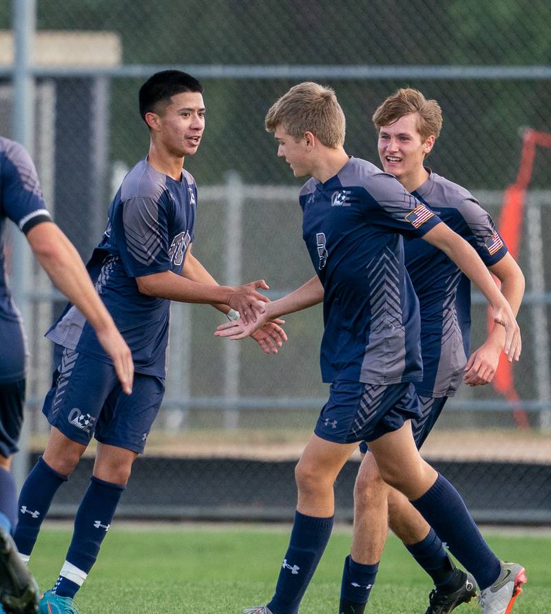 Oswego East's Israel Torres (10) left is greeted by team members after scoring a goal against Oswego during a soccer match at Oswego East High School on Monday, Sep 26, 2022.