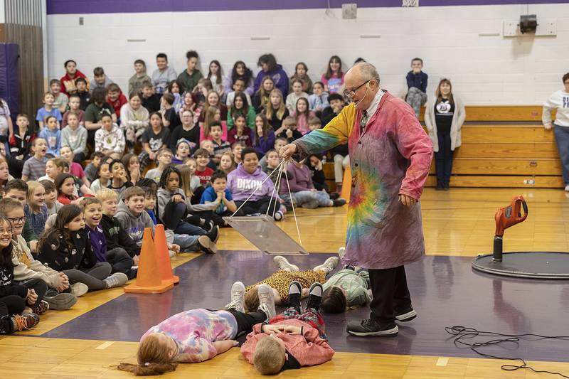 Steve Belliveau spins a cup of water over four Madison School students Friday, March 7, 2025, during his “Getting Excited About Science” program.