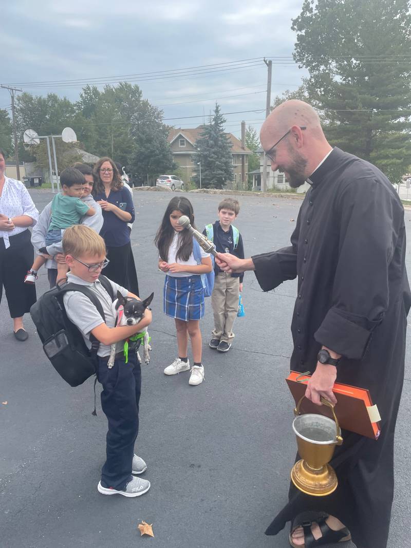 Hey, watch where you're throwing that holy water. Skyler Steinbach, 8, of Peru leans back to avoid getting splashed by the Very Rev. Thomas Otto, pastor of the La Salle Catholic Parishes, during the yearly blessing of the animals held Wednesday, Oct. 4, 2023, outside St. Patrick Catholic Church, La Salle. Otto's holy water was aimed at Peanut, Skyler's chihuahua. Oct. 4 is the feast of St. Francis of Assisi, an animal lover who inspired a custom of blessing household pets.