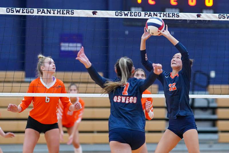 Oswego’s Ava Flanigan (12) sets the ball during a volleyball match against Minooka at Oswego High School on Thursday, Oct. 3, 2024.