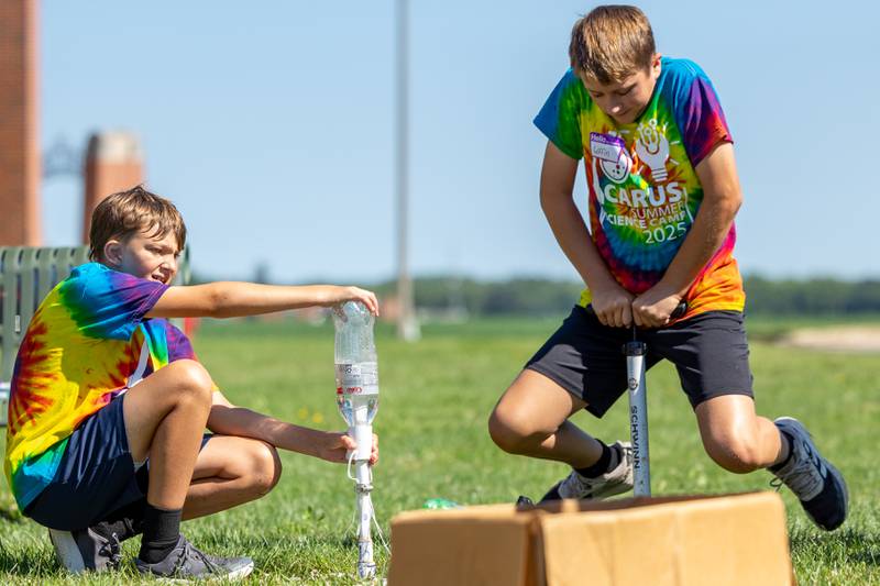 (left to right) Blake holds down rocket launcher as Griffin jumps on lever to shoot off two liter bottle rocket at the 23rd annual Carus Summer Science Camp on Friday, July 18, 2025 at St. Bede High School in Peru.