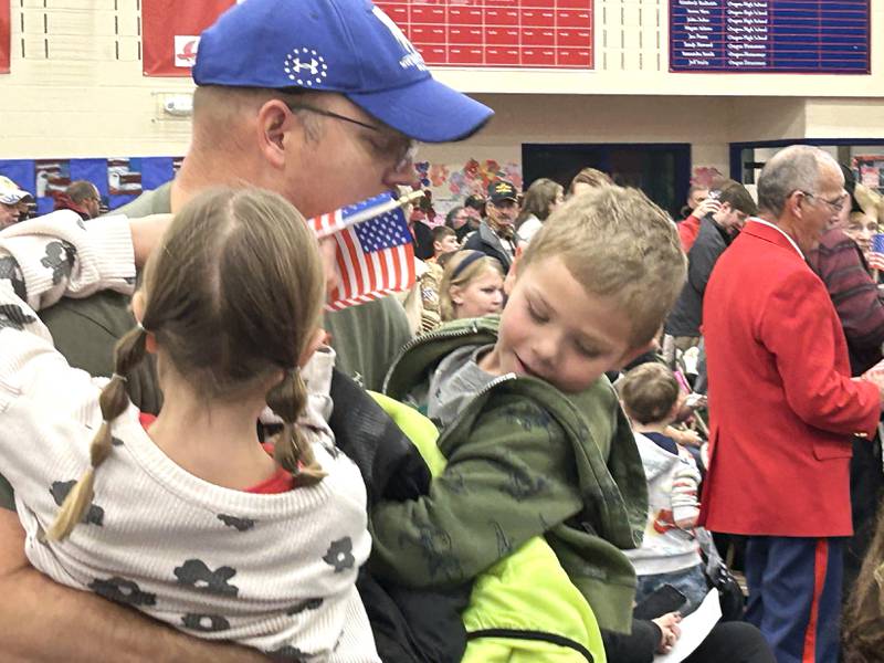 Navy veteran Matt Dressman gets a flag and hugs from his kids Amelia and Elijah during the Oregon School District's Veterans Day Assembly on Tuesday, Nov. 11, 2025. The event was held Tuesday morning in the Blackhawk Center to thank veterans for their service.