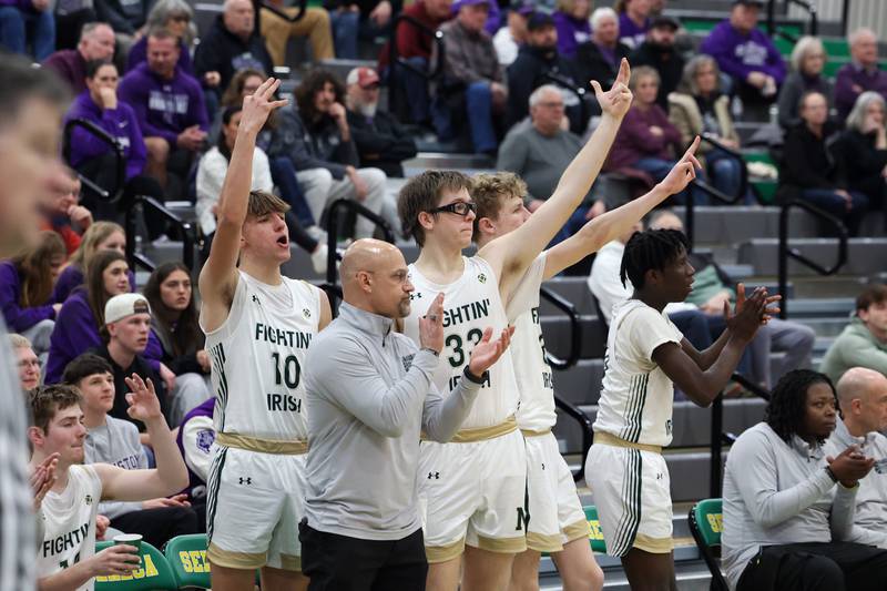 Bishop McNamara head coach Adrian Provost and players celebrate a 3-pointer during the Fightin' Irish's 61-24 victory over Wilmington in the IHSA Class 2A Seneca Sectional semifinal on Tuesday, March 3, 2026.