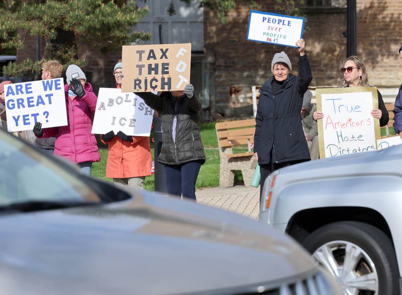 Vehicles on First Street pass protesters Friday, May 1, 2026, during a May Day rally at Memorial Park in downtown DeKalb. The group gathered to advocate for workers’ rights and push for billionaires to be taxed amid cost-of-living burdens they argue are hurting everyday Americans.