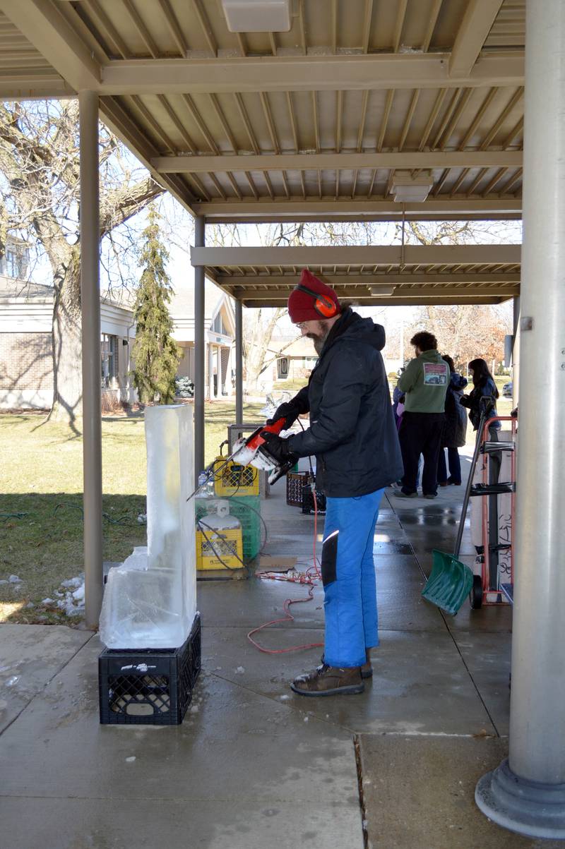 Robert Storm carves a block of ice outside the Rock Falls Community Center on Saturday, Feb. 10, 2024.