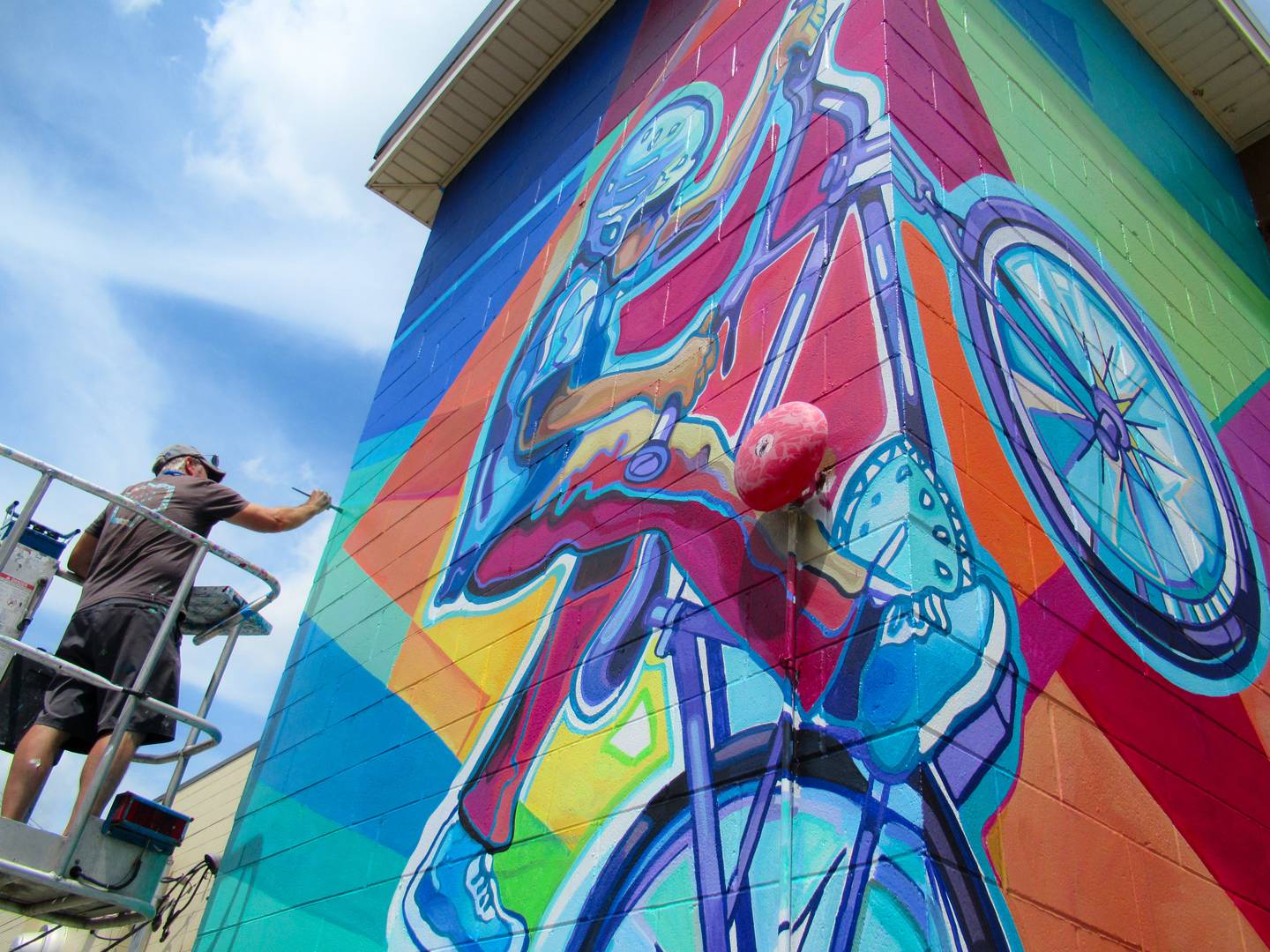 Jason Watts putting the finishing touches on his mural at 59 Main St. in downtown Oswego.