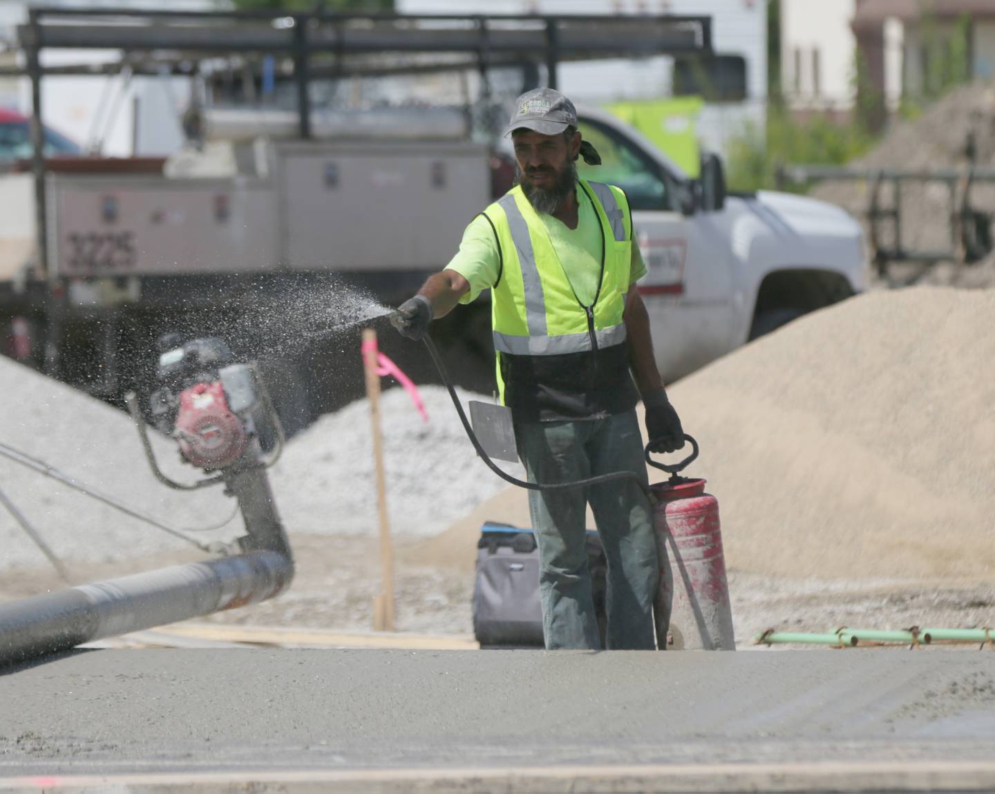 A worker sprays water on freshly paved concrete at the roundabout site of the intersection of 178 and U.S. Route 6 on Thursday, Sept. 1, 2022 in Utica.