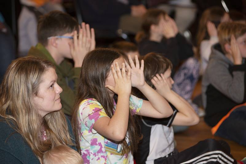 Kids use their hands to mimic the eyesight limitations of an owl during the Hoo Haven program Wednesday, April 13, 2022 at White Pines Resort. Owls can’t see peripheral or move their eyes, but extra vertebra allows them to turn their heads over 180 degrees.