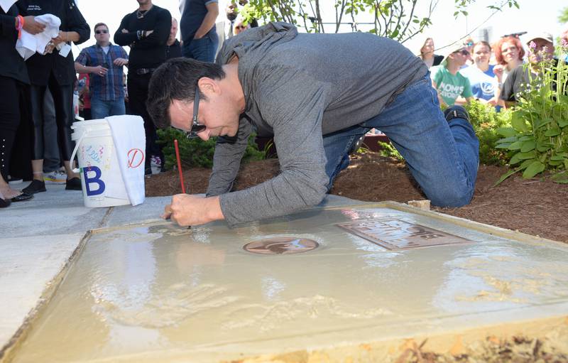 Jordan Knight signs his name an places a hand print in wet cement during the Wahlk of Fame Ceremony for New Kids on the Block at the Wahlburgers in St. Charles on Saturday, June 18, 2022.