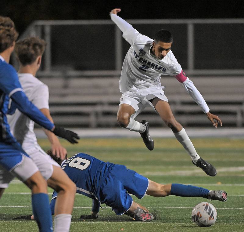 St. Charles North’s Diego Torres leaps over Geneva’s Reece Leonard in a boys soccer game in Geneva on Tuesday, Oct. 15, 2024.
