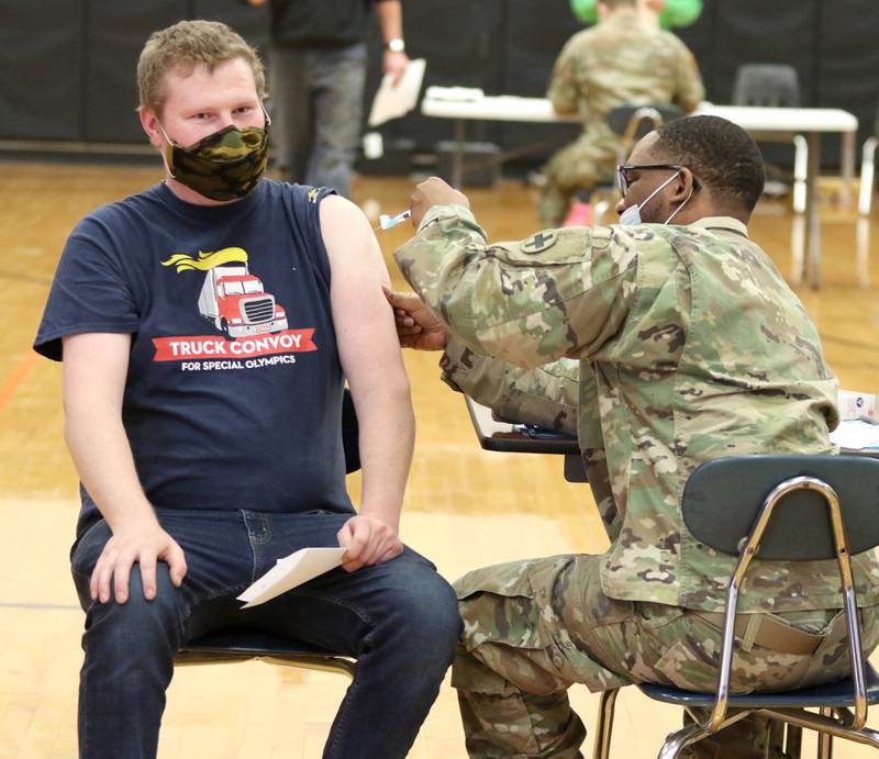 A member of the Illinois National Guard administers a dose of the COVID-19 vaccine to Arron Nicklas, from Sandwich, during the DeKalb County Health Department clinic Thursday at Sandwich High School.