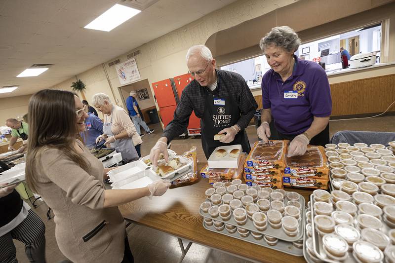 Volunteer Darla Russell accepts rolls from Leo and Linda Patterson Thursday, Nov. 24, 2022 at the Knights of Columbus’ Thanksgiving meal in Dixon. Volunteers lined up with trays while others served the the traditional Thanksgiving dinner.