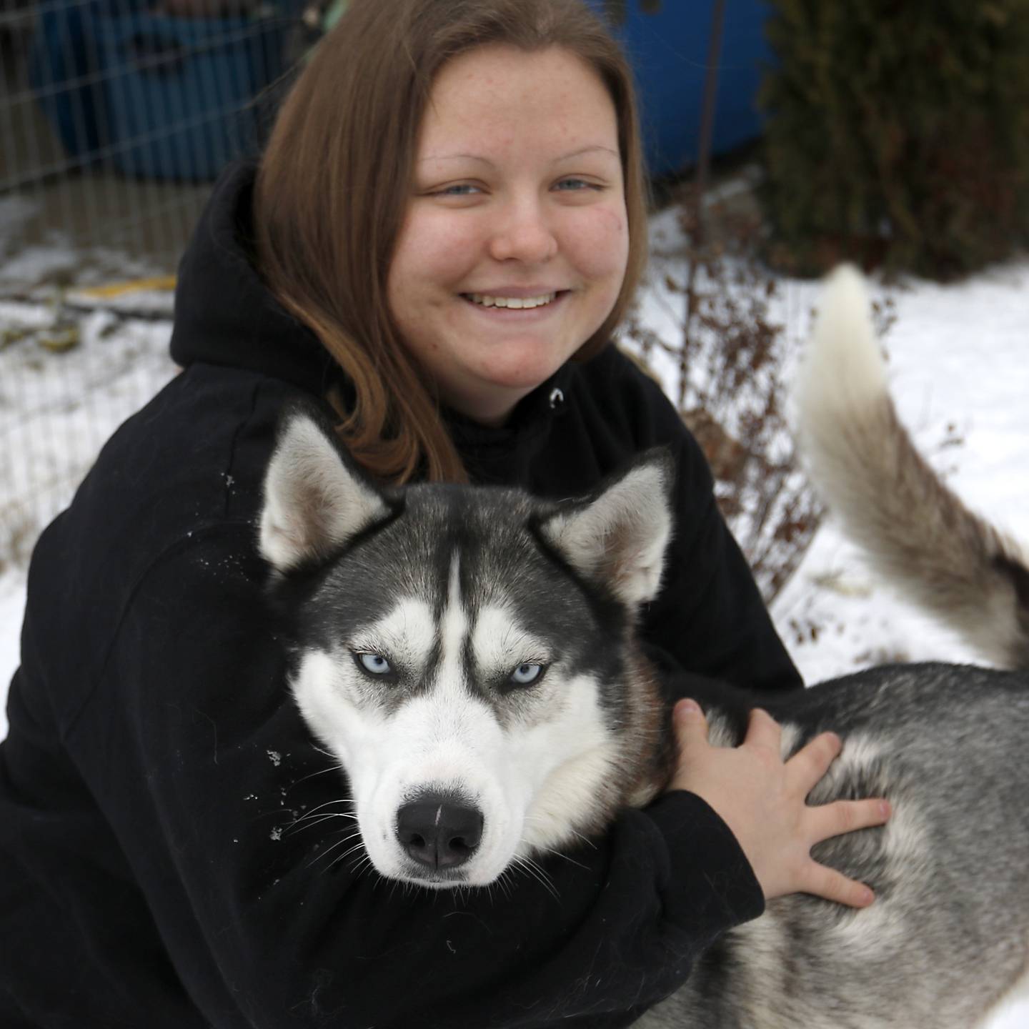 Hanna Kowal abraza a Arloc, uno de sus perros de trineo, el martes 20 de diciembre de 2022 en su casa cerca de Hebrón.  Koala entrena y compite con perros de trineo mientras trabaja y va a la universidad.