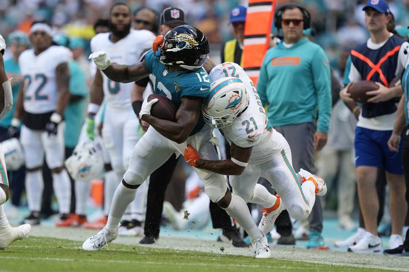 Miami Dolphins safety Jordan Poyer (21) tackles Jacksonville Jaguars wide receiver Devin Duvernay (12) during the second half of an NFL football game, Sunday, Sept. 8, 2024, in Miami Gardens, Fla. (AP Photo/Rebecca Blackwell)