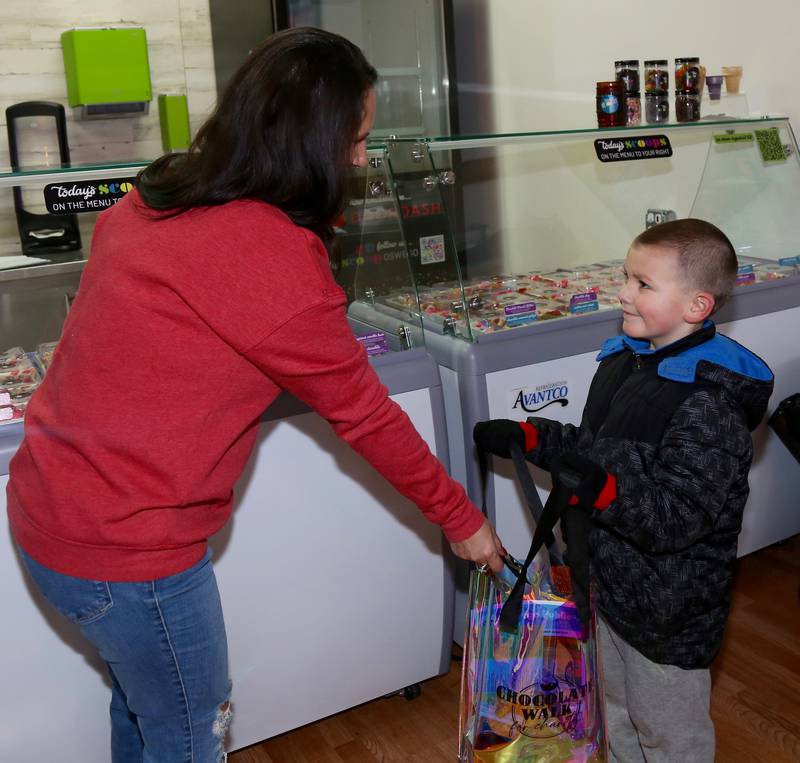 Christina Reynolds of Scoop gives Ryan Lang, 6, chocolate as part of the 8th Annual Chocolate Walk for Charity in Oswego on Saturday, Feb. 8, 2025.
