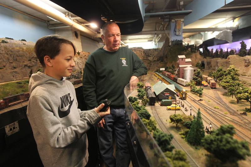 Alex Keith, 11, talks with Frank Blacker, both of Wauconda, on Dec. 26 about stopping a Chicago Northwestern passenger train as it pulls into the Lake Geneva station at the Lake County Model Railroad Club in Wauconda. Alex is holding a controller to guide the train. The club is celebrating its 50th anniversary.