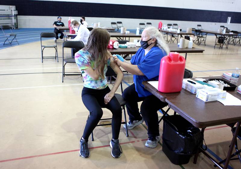 Raina Murphy, 13, receives a COVID-19 vaccine from pharmacy technician Lori Oldenburg during a vaccination clinic put on by Osco and Hinsdale Township High School District 86 at Downers Grove South High School on Wednesday, May 26, 2021.