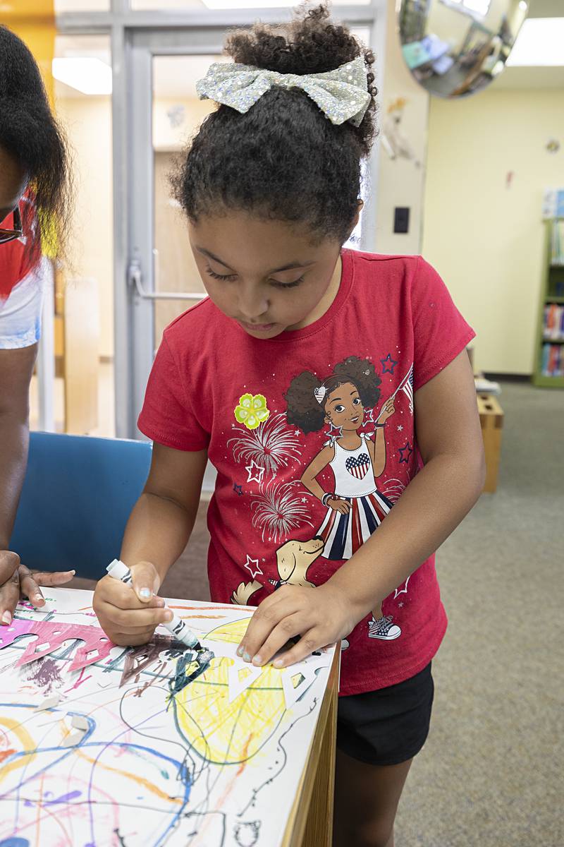 Mickinzy Sandoval, 7, of Dixon colors in a crown Wednesday, July 3, 2024 at the Dixon library as part of the crafts with Petunia royalty event.