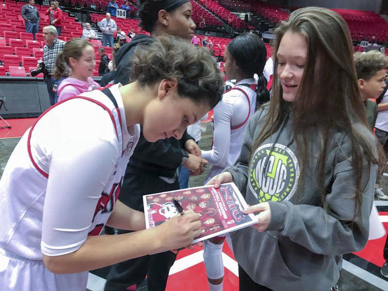 NIU guard Paulina Castro (24) signs a NIU game program for Clinton-Rosette eighth grader Ashley Sheriff, 13, at The NIU Convocation Center in DeKalb December 6.