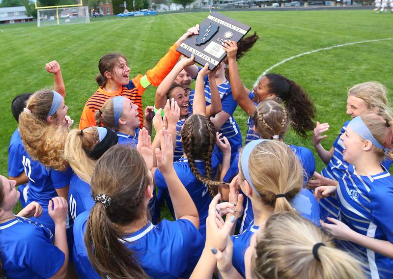 Members of the Princeton girls soccer team celebrate while hoisting the Class 1A Regional final plaque after shutting out Genoa-Kingston on Friday, May 13, 2022 in Princeton.