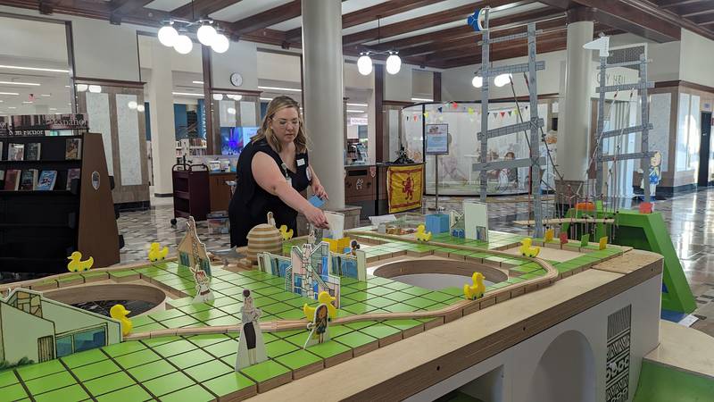 Mallory Hewlett, communications manager at the Joliet Public Library, shows one of the interactive displays in the “The Questioneers: Read. Question. Think. PLAY!” exhibit on Wednesday, June 21, 2023. This exhibit is based on the Questioneers book series authored by Andrea Beaty and illustrated by David Roberts. This traveling exhibit featuring the Questioneers characters opened June 16 at the Ottawa Street branch of the Joliet Public Library and is available during library hours through July 29.