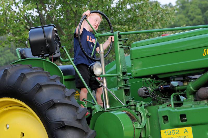 Four-year-old Carter Garbe of Seneca couldn't be happier to be driving a 1952 John Deere tractor owned by J.D. Hartman during the Kendall County Fair in Yorkville on Friday, Aug. 2, 2024.