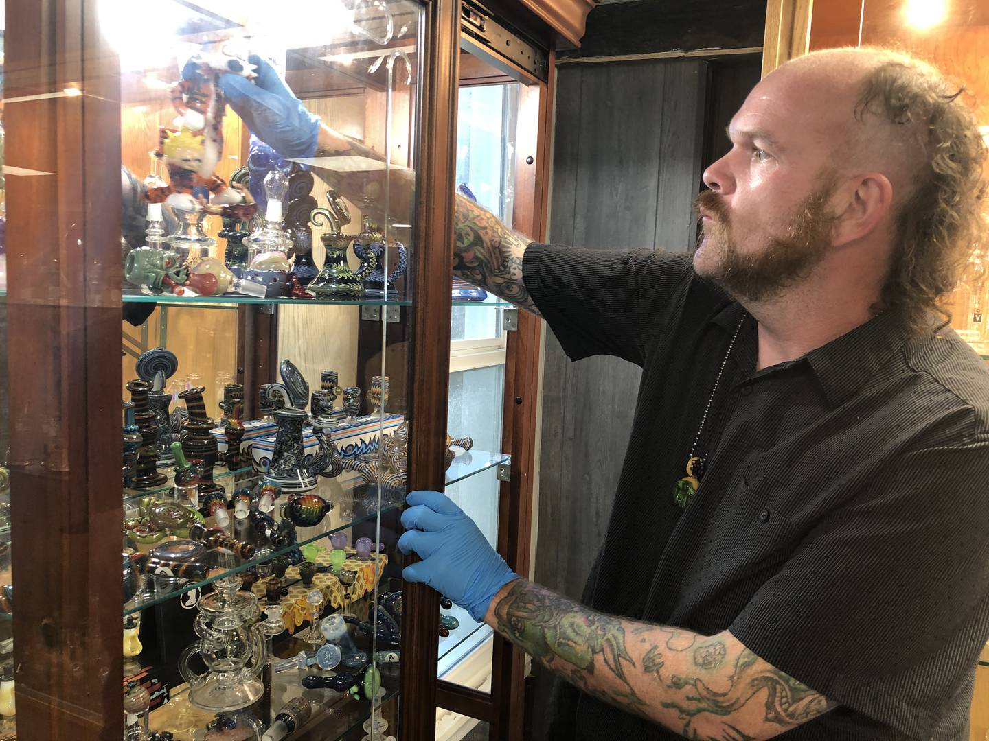 Cameron Clark, owner of Otto’s in McHenry, displays some of the glasswork available in the store on July 18, 2022. The store, which opened in June, offers several levels of Venetian-style glass blowing classes.