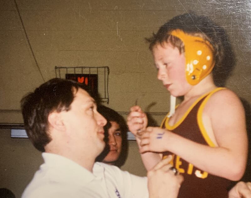 Princeton High School wrestling coach Steve Amy, about age 9 in this photo, gets instructions from his dad, Rick, during a youth match 30 years ago. Rick Amy died in 2021, but left a legacy with his son, who has coached at PHS since 2008.