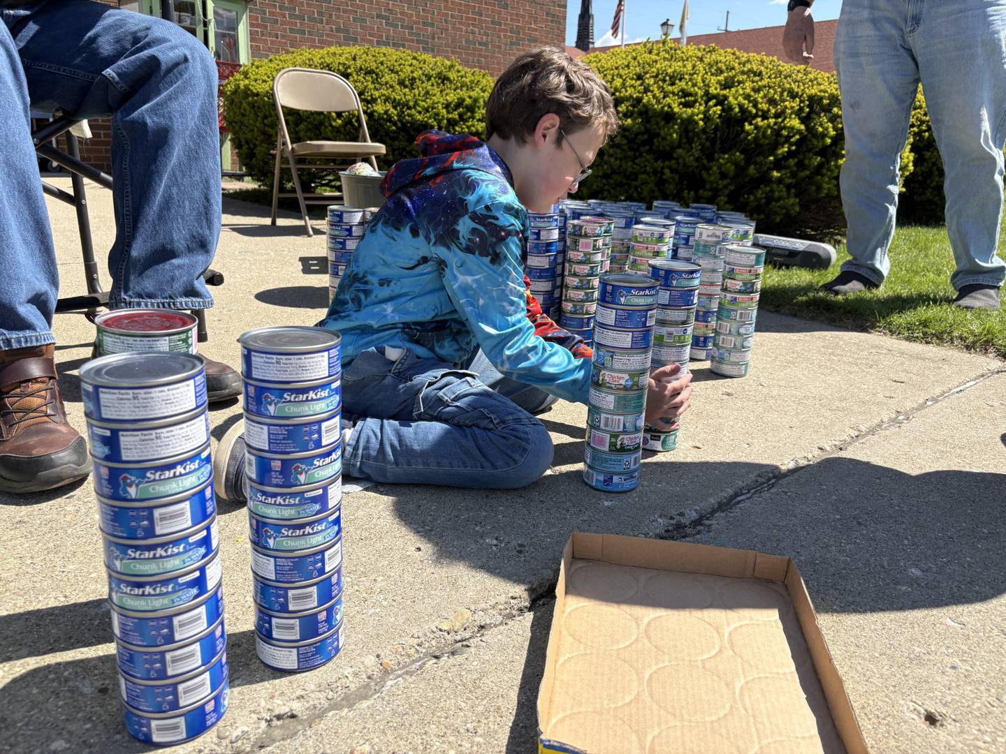 Maximilian Claahsen stacks donated tuna cans during his annual birthday food drive Saturday, May 2, outside the Marseilles Food Pantry.