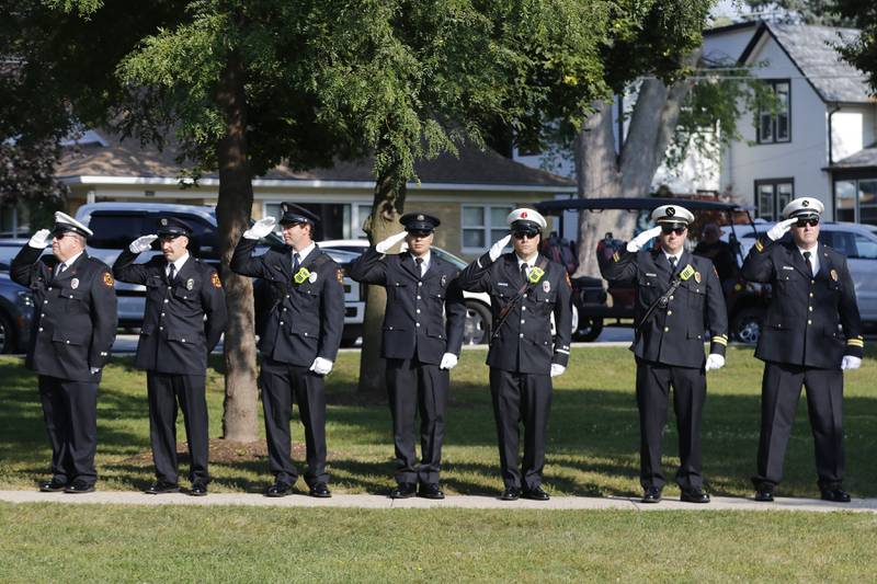 McHenry Township Fire Protection District firefighters salute as the American Flag is raided during a September 11 Remembrance Ceremony on Sept. 11, 2025, at Veterans Park in McHenry.