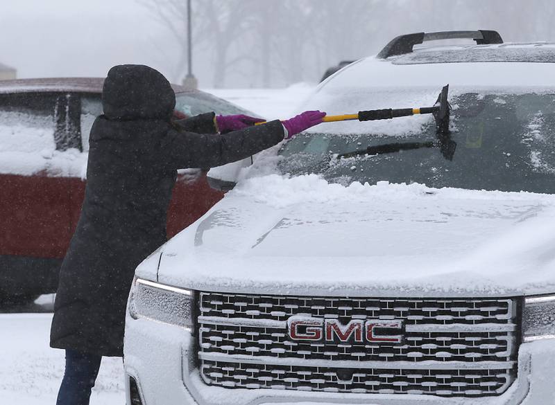 Teacher Leah Pinkowski cleans the windows of her car Thursday, Feb. 16, 2023, at Richmond-Burton Community High School in Richmond, after a winter storm moved through McHenry County creating hazardous driving conditions.