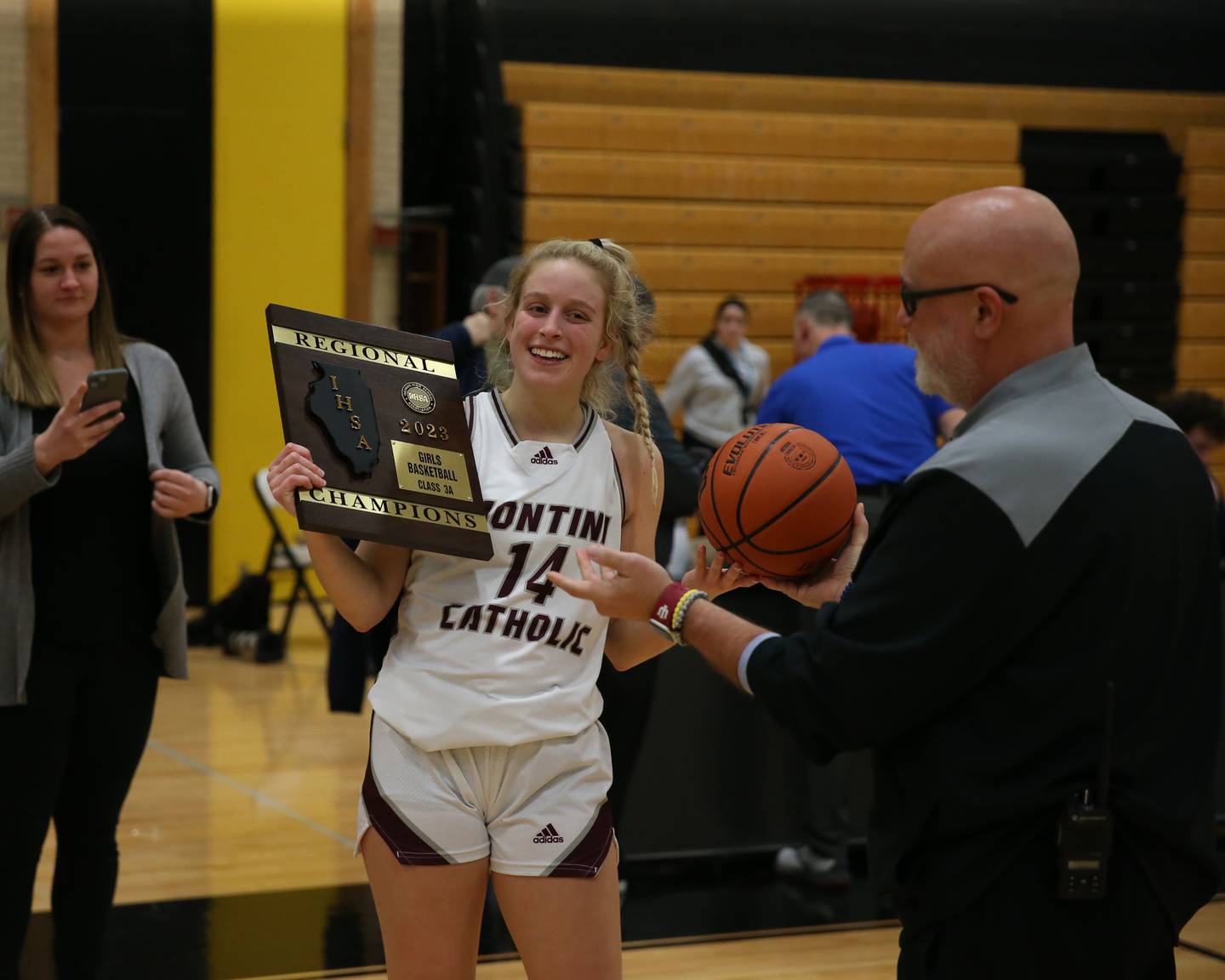 Montini Catholic's Shannon Blacher (14) holds the Class 3A Hinsdale South Regional final plaque after their win over Glenbard South.  Feb 17, 2023.