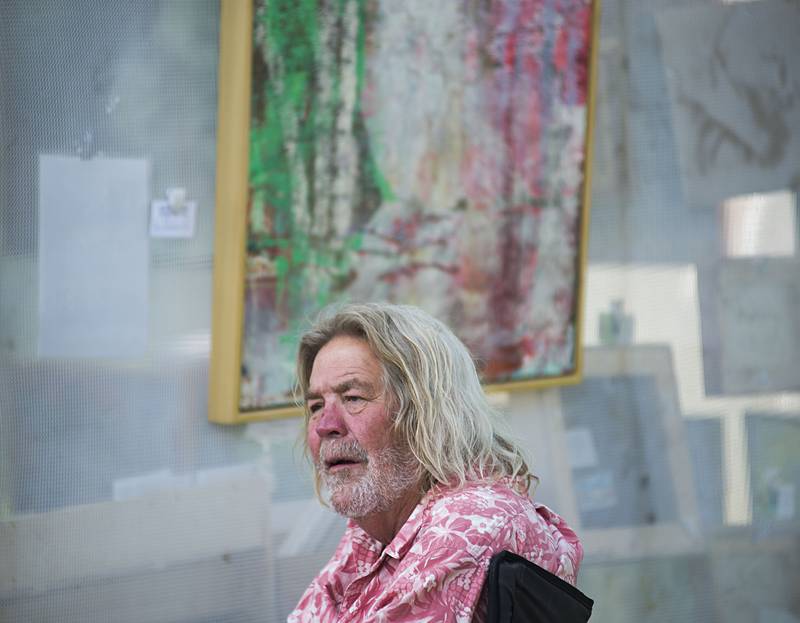 Artist Kent Broadbent sits outside his tent Saturday, July 2, 2022, framed by some of the abstract art he has for sale at Nuts About Art in Dixon. The annual art in the park event brought in artists of many medium selling their works.