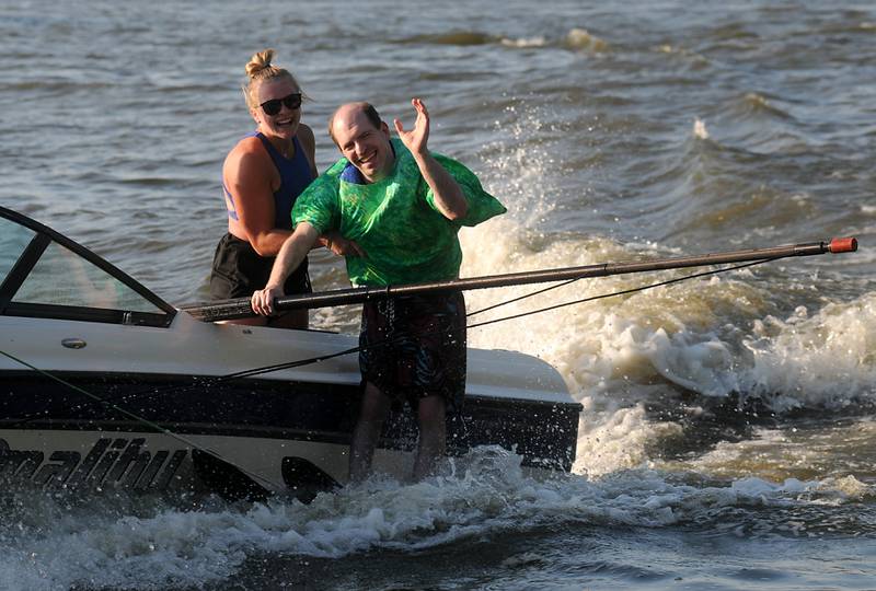 With the help of Abby Hartmann, Erik Hoary waves to the crowd as he water skis Tuesday, June 21, 2022, while performing in the Wonder Lake Water Ski Show Team and Northern Illinois Special Recreation Association’s show on Wonder Lake. The performance was the end of the team’s learn to ski clinic. Members of ski team have constructed adaptive water ski equipment, which has proven year after year to be successful in allowing every participant to be able to water ski.