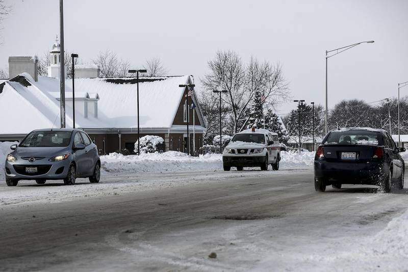 Cars drive Tuesday on a snow-covered Black Road in Joliet.