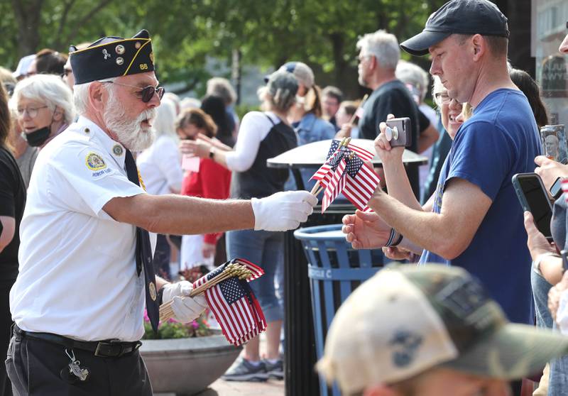 A member of the DeKalb American Legion Post 66 hands out flags Monday, May 29, 2023, during the DeKalb Memorial Day parade.