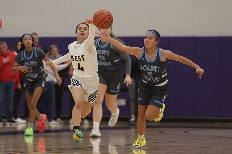 Joliet West’s Christina Keoborakot knocks the ball away from Joliet Catholic’s Elena Czerkies in the WJOL Basketball Tournament at Joliet Junior College Event Center on Monday