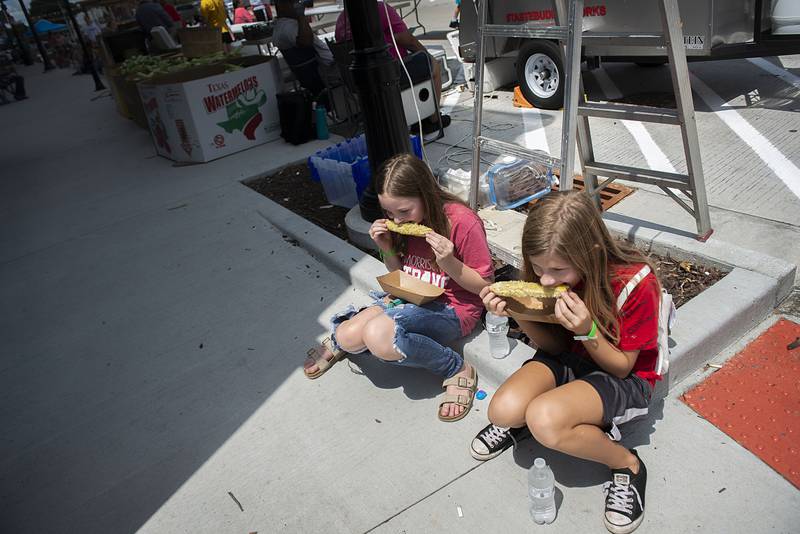 Elliott-Jo Armstrong (left), 11, and Kolbie Theodore, 11, of Morrison dig into some roasted sweet corn Saturday, July 30, 2022 at Morrison’s first ever Shuckfest. The first time festival featured music, food, vendors and fun and games for the kids.