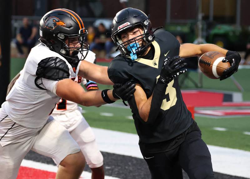 Sycamore punter Benjamin Anderson just gets the ball out of the endzone after a bad snap before being pushed out of bounds by DeKalb's Ryan Welsh Friday, Aug. 29, 2025, during the FNBO Challenge in Huskie Stadium at Northern Illinois University.