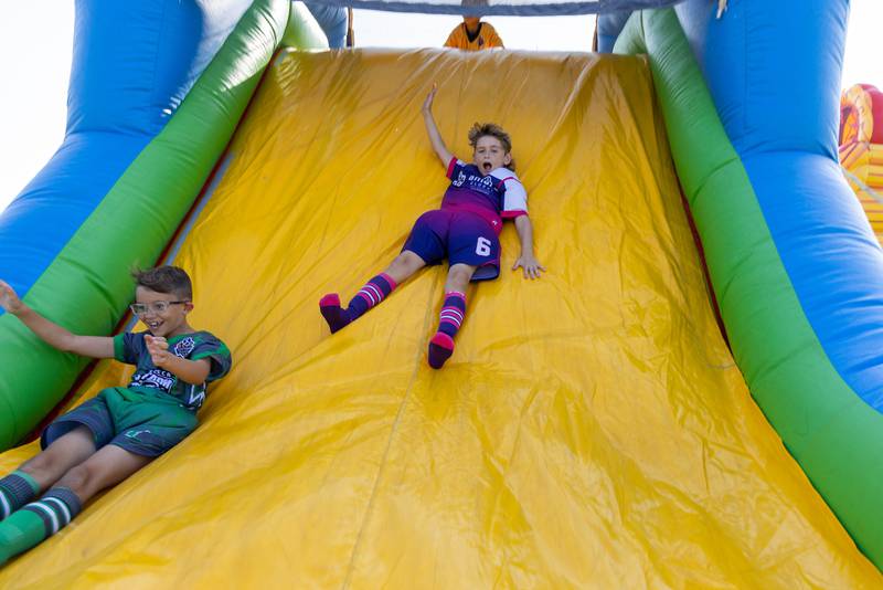 Players and their families enjoy a bounce house and slides Saturday, Aug. 19, 2023, at Ottawa Soccer Club's season opening celebration.
