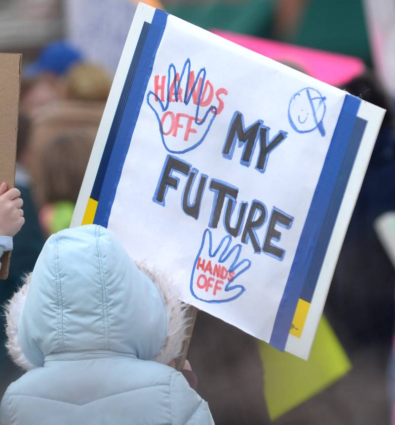 A young girl holds a sign during the Hands Off rally around the historic Ogle County Courthouse in Oregon on Saturday, April 5, 2025.