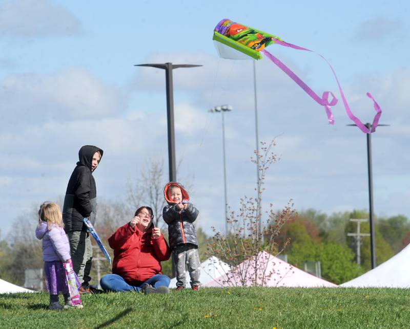 Tiffany Hunter of Montgomery, helps her kids Hannah, 2, John, 9 and George, 4 lauch a kite during a celebration of Earth Day and National Kite Month at Prairie Point Park in Oswego, Saturday, April 20, 2024.