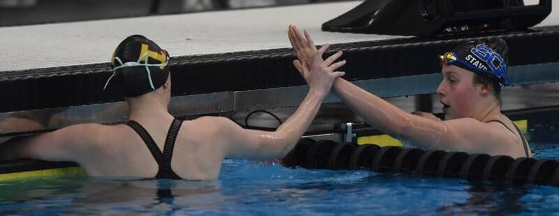 St. Ignatius’ Julieta Tracy, left, and St. Charlles North’s Tessalina Stavropoulos high-five one another at the conclusion of the 100-yard freestyle during the IHSA girls state swimming finals at FMC Natatorium in Westmont on Saturday, Nov. 12, 2022.
