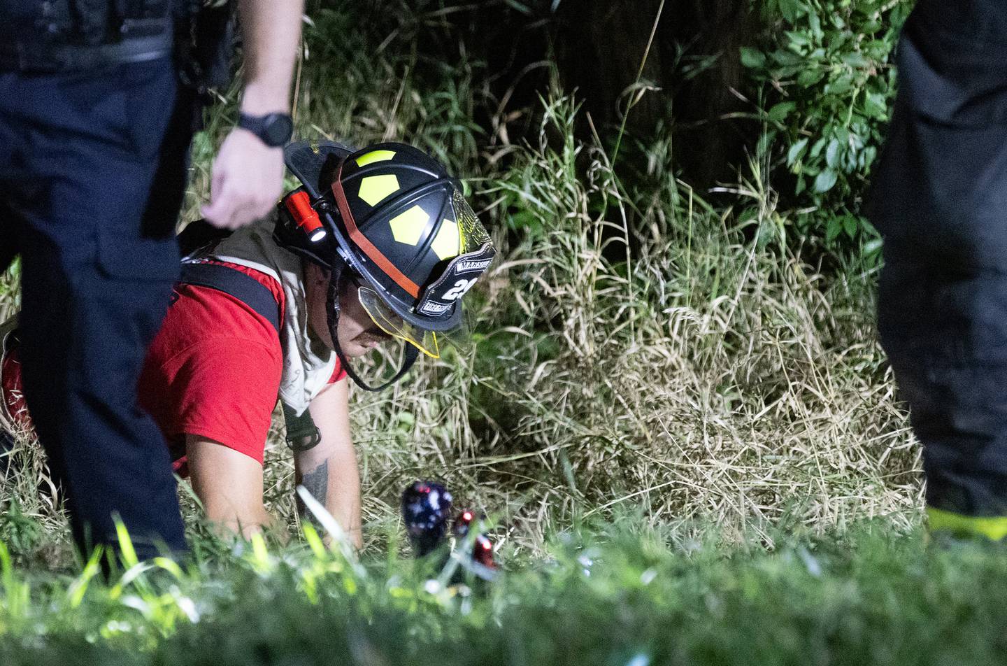 A Marseilles firefighter searches the area of the crash Friday, Oct. 4, 2024, for something in the grass. About half a dozen more first responders aided in the search.